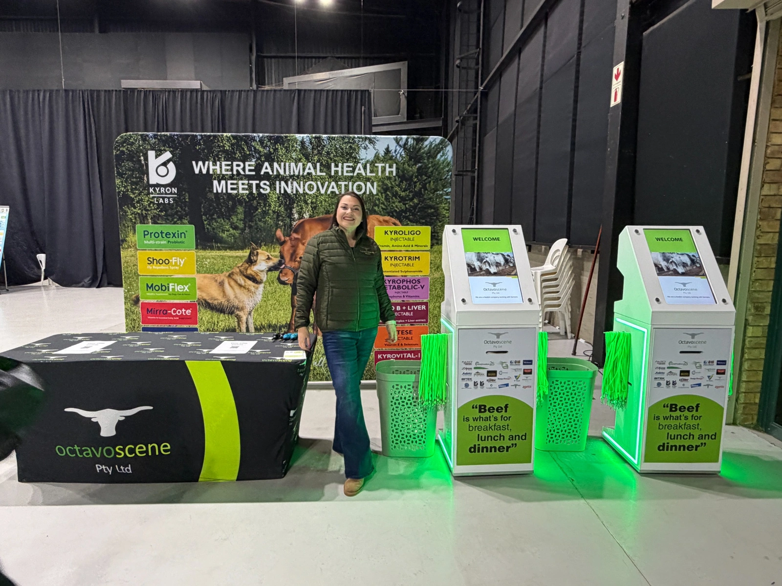 Event representative beside branded self-service registration kiosks at a live exhibition