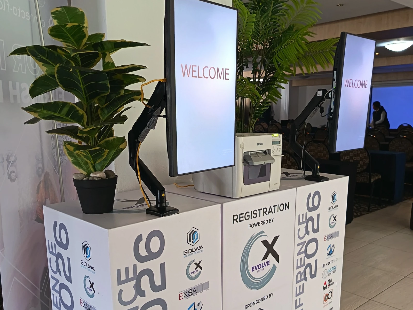 Conference registration desk with welcome screens and onsite badge printing equipment